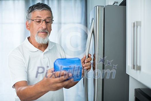 Is this still fine? Senior man in his kitchen by the fridge, looking at the expiry date of a product she took from her fridge - Is this still fine? Senior man in his kitchen by the fridge, looking at the expiry date of a product she took from her fridge -