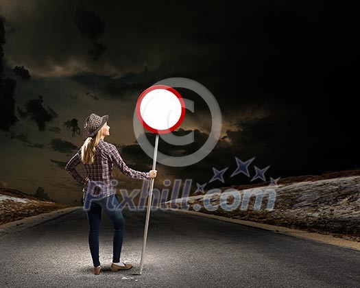Young woman in casual holding road sign Young woman in casual holding road sign