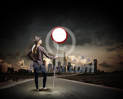 Young woman in casual holding road sign Young woman in casual holding road sign