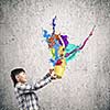 Cute boy splashing colorful paint from bucket