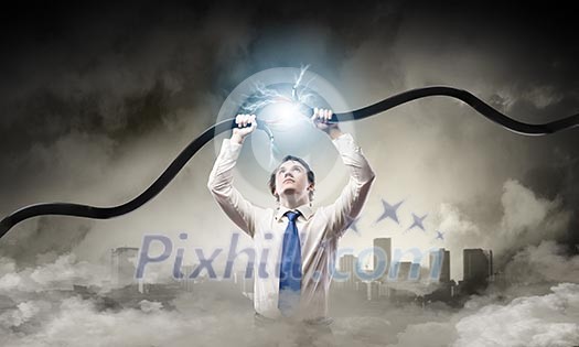 Young businessman tearing electricity cable with hands Young businessman tearing electricity cable with hands