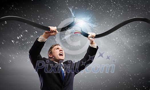 Young businessman tearing electricity cable with hands
