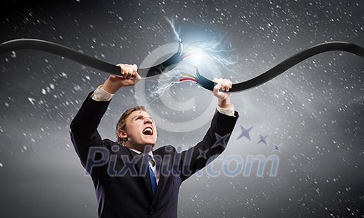 Young businessman tearing electricity cable with hands Young businessman tearing electricity cable with hands