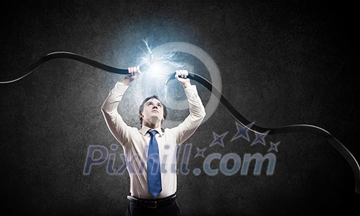 Young businessman tearing electricity cable with hands Young businessman tearing electricity cable with hands