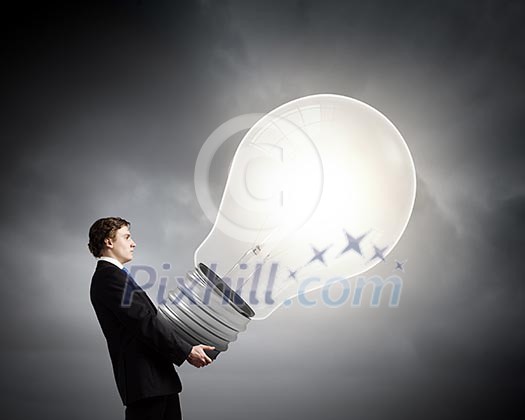 Young businessman carrying big heavy light bulb Young businessman carrying big heavy light bulb