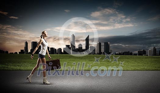 Young woman hiker walking with suitcase in hand