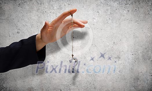Close up of male hand holding question mark on rope Close up of male hand holding question mark on rope