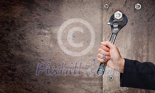 Close up of businessman hand fixing mechanism with spanner