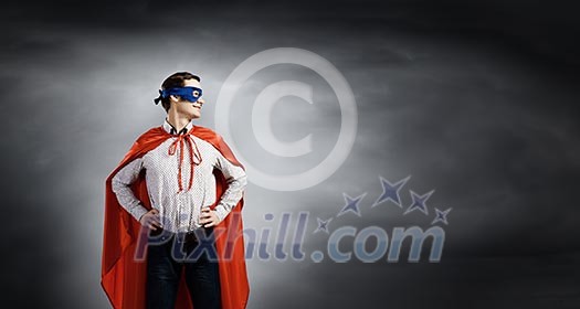 Young confident superman in mask and cape