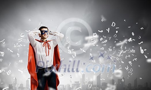 Young man in hero costume closing ears with palms Young man in hero costume closing ears with palms