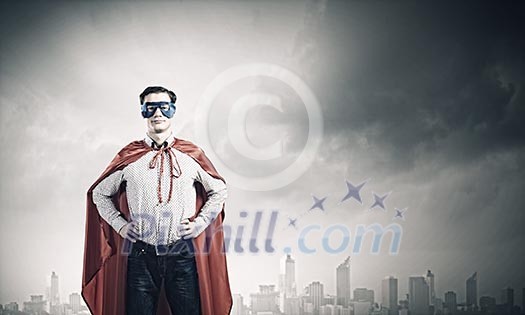 Young confident superman in mask and cape