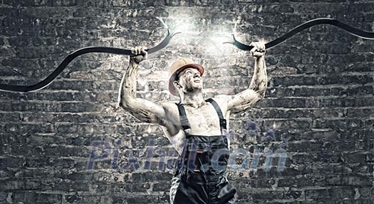 Strong man in uniform tearing electricity cable with hands Strong man in uniform tearing electricity cable with hands