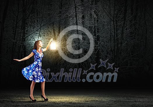 Young woman in blue dress walking in night wood