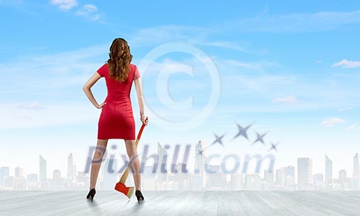 Rear view of woman in red dress with axe in hand