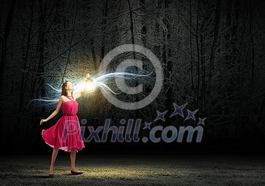 Young woman in red dress walking in night wood