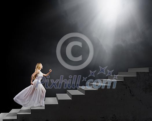 Young woman in white long dress walking up the staircase Young woman in white long dress walking up the staircase