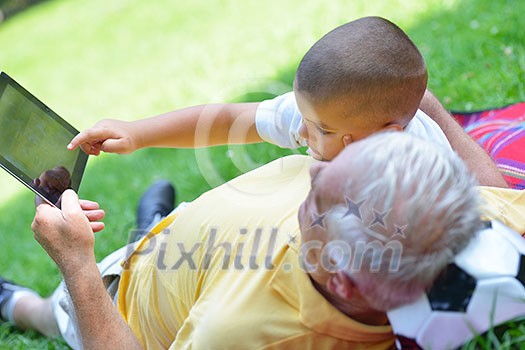 grandfather and child in park using tablet computer grandfather and child in park using tablet computer