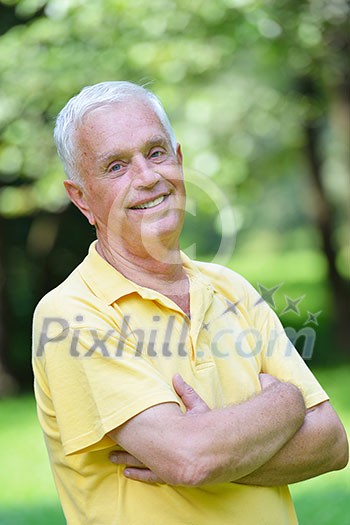 happy healthy and fit elderly man portrait  in green background park