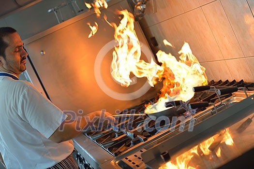 Handsome chef dressed in white uniform decorating pasta salad and seafood fish in modern kitchen Handsome chef dressed in white uniform decorating pasta salad and seafood fish in modern kitchen