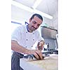 Handsome chef dressed in white uniform decorating pasta salad and seafood fish in modern kitchen