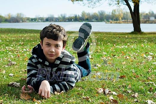 Cute boy  in autumn park laying on grass 