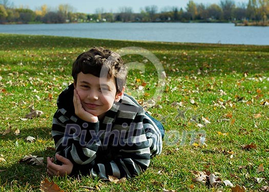 Cute boy in autumn park laying on grass Cute boy in autumn park laying on grass