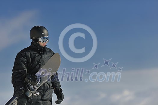 snowboarder relaxing and posing at sunny day on winter season with blue sky in background snowboarder relaxing and posing at sunny day on winter season with blue sky in background