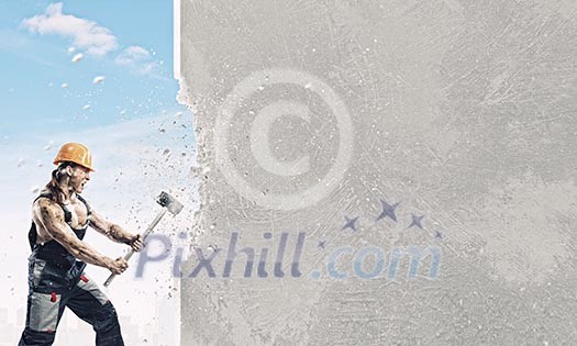 Strong man in uniform breaking brick wall with hammer