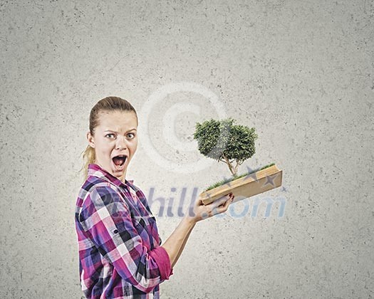 Young woman in casual holding opened book with green tree Young woman in casual holding opened book with green tree