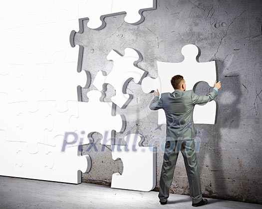 Image of businessman compiling macro white puzzle. Building business