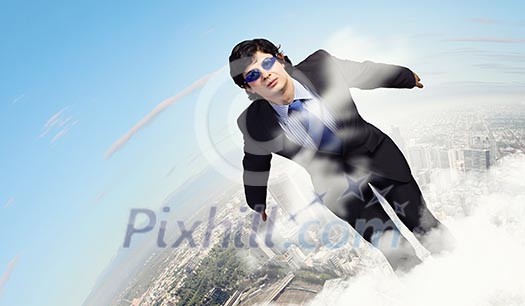 Image of young businessman in goggles jumping from top of building Image of young businessman in goggles jumping from top of building