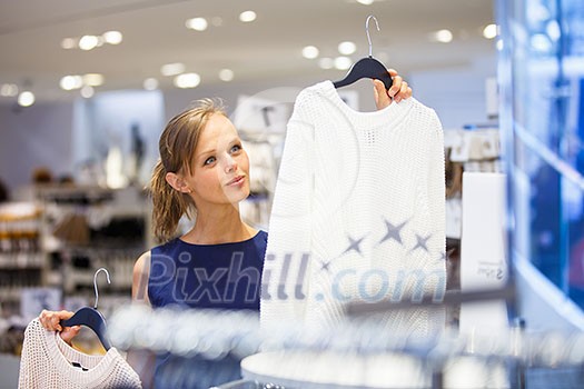 Beautiful young female shopper in a clothing store, chossing a blouse/t-shirt/garments (shallow DOF; color toned image) Beautiful young female shopper in a clothing store, chossing a blouse/t-shirt/garments (shallow DOF; color toned image)