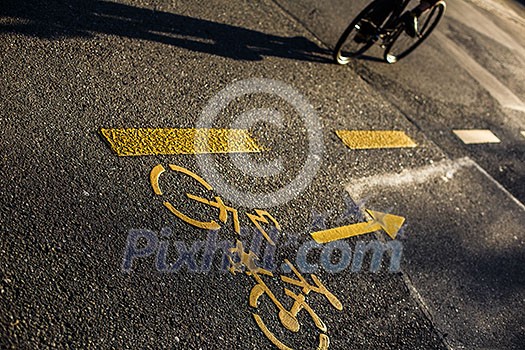 Biker/Cyclist on a crossing in a city casting a long shadow Biker/Cyclist on a crossing in a city casting a long shadow
