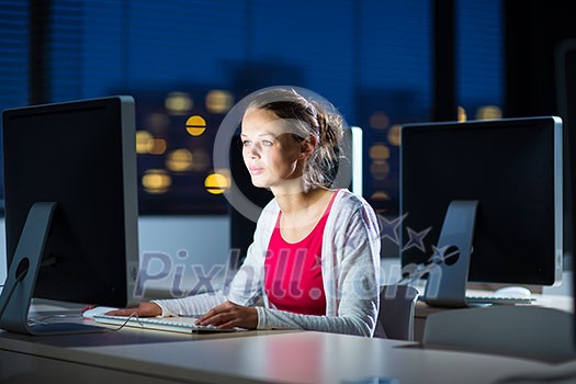 Pretty, young female college student using a desktop computer/pc in a college library (shallow DOF; color toned image)