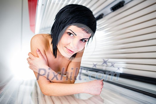 Pretty, young woman tanning her skin in a modern sunbed