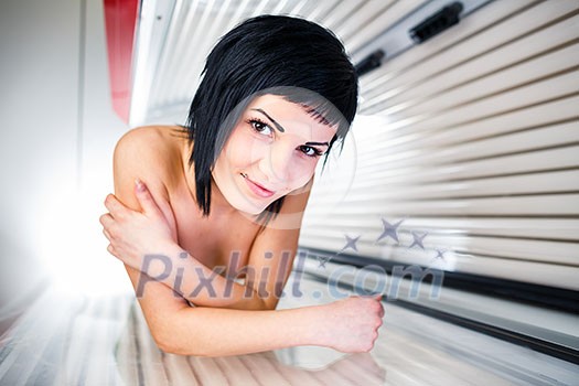Pretty, young woman tanning her skin in a modern sunbed Pretty, young woman tanning her skin in a modern sunbed