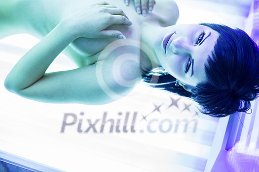 Pretty, young woman tanning her skin in a modern solarium/sunbed Pretty, young woman tanning her skin in a modern solarium/sunbed