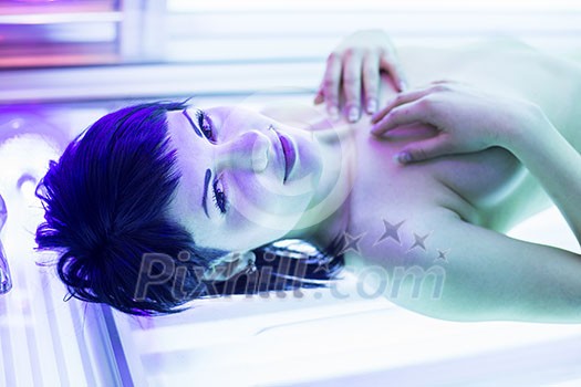 Pretty, young woman tanning her skin in a modern solarium/sunbed Pretty, young woman tanning her skin in a modern solarium/sunbed