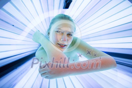Pretty, young woman tanning her skin in a modern solarium/sunbed Pretty, young woman tanning her skin in a modern solarium/sunbed