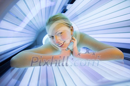 Pretty, young woman tanning her skin in a modern solarium/sunbed Pretty, young woman tanning her skin in a modern solarium/sunbed