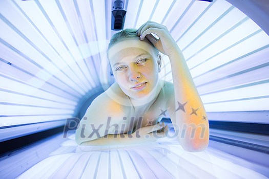 Pretty, young woman tanning her skin in a modern solarium/sunbed Pretty, young woman tanning her skin in a modern solarium/sunbed