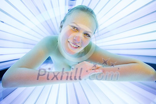 Pretty, young woman tanning her skin in a modern solarium/sunbed Pretty, young woman tanning her skin in a modern solarium/sunbed