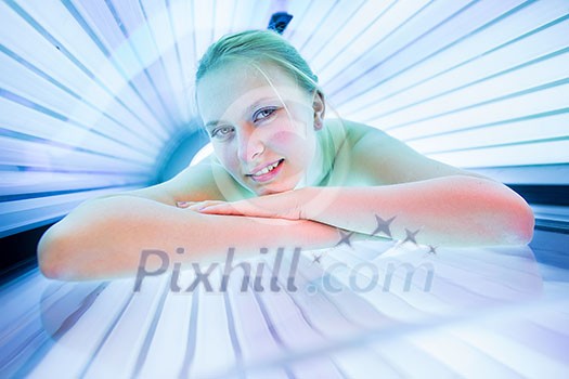 Pretty, young woman tanning her skin in a modern solarium/sunbed Pretty, young woman tanning her skin in a modern solarium/sunbed