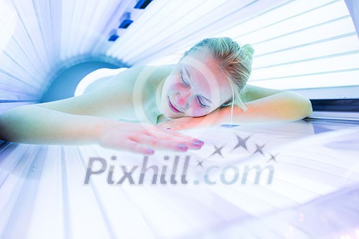 Pretty, young woman tanning her skin in a modern solarium/sunbed Pretty, young woman tanning her skin in a modern solarium/sunbed