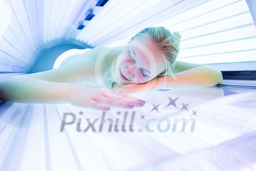 Pretty, young woman tanning her skin in a modern solarium/sunbed