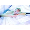Pretty, young woman tanning her skin in a modern solarium/sunbed
