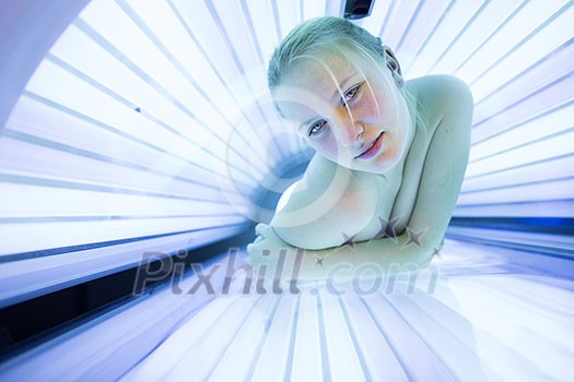 Pretty, young woman tanning her skin in a modern solarium/sunbed