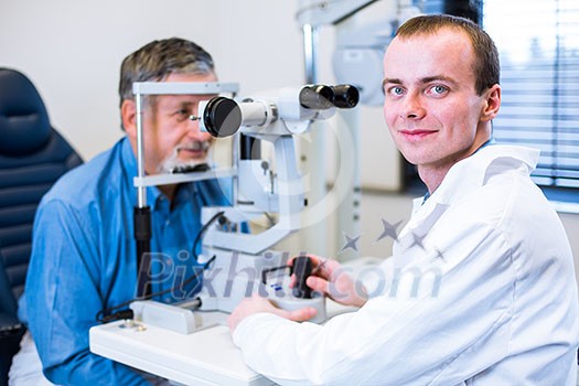 Optometry concept - senior man having his eyes examined by an eye doctor (color toned image; shallow DOF)