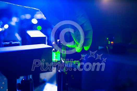Quantum optics - hand of a researcher adjusting a laser beam in a lab Quantum optics - hand of a researcher adjusting a laser beam in a lab