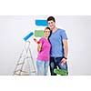 happy young couple paint in green and blue color white wall of their new home